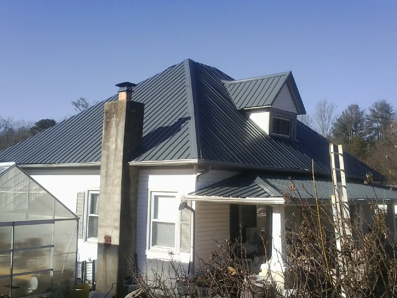 Dark blue standing seam metal roof on a white farmhouse with dormer — Slate & Tile Roof Repair by Roofing Brothers in Holtwood