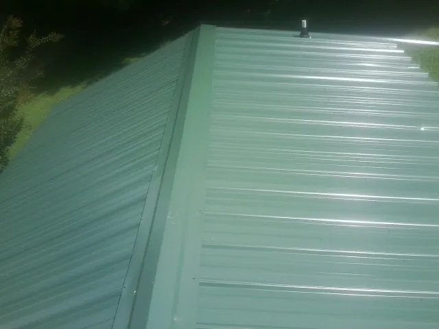 New green metal panels meeting at the ridge of a roof — Flat Roof Repair work by our crew in Holtwood