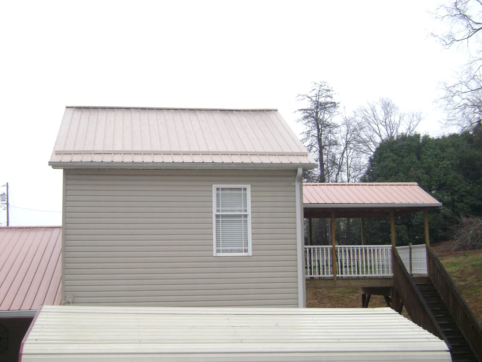 Tan metal roofs on a two story addition and attached porch, from a Roof Replacement job in Holtwood