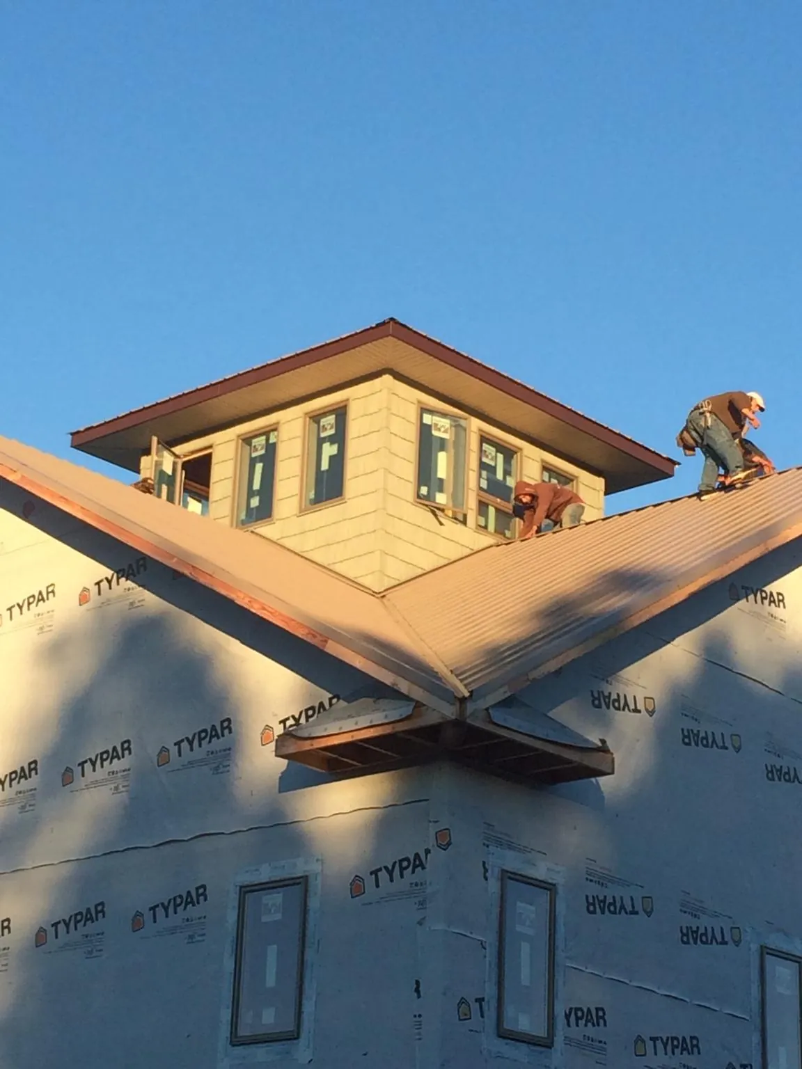 Roofers working around a rooftop cupola on a new metal roof at sunset — Roof Waterproofing in Holtwood by Roofing Brothers